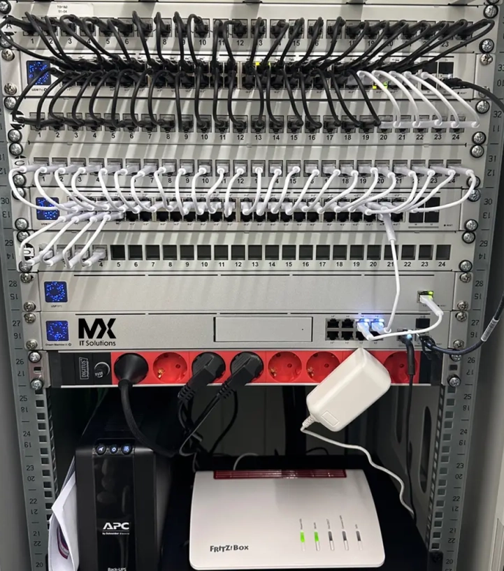 Ein perfekt organisiertes Netzwerkrack in einem Serverraum, mit sorgfeltigen Ethernet-Kabeln in verschiedenen Farben, die ordentlich geführt werden. Die Kabel sind nach Funktion und Bestimmungsort sortiert, was eine klare und übersichtliche Struktur schafft. Hintergrund zeigt die kühle, blaue Beleuchtung des Serverraums, die die Präzision und Sauberkeit der Installation unterstreicht. Ein visuelles Beispiel für effiziente und ästhetische Netzwerkverteilung.